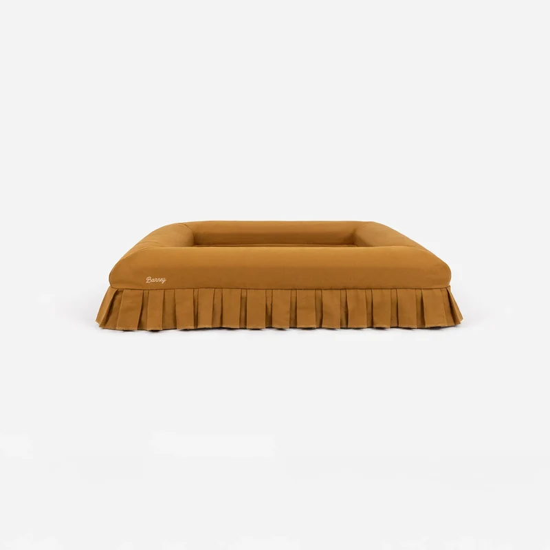 Nostalgia Cover in Toffee: the bed on its own from the front, toffee brown with pleated skirt and cream script "Barney" logo.