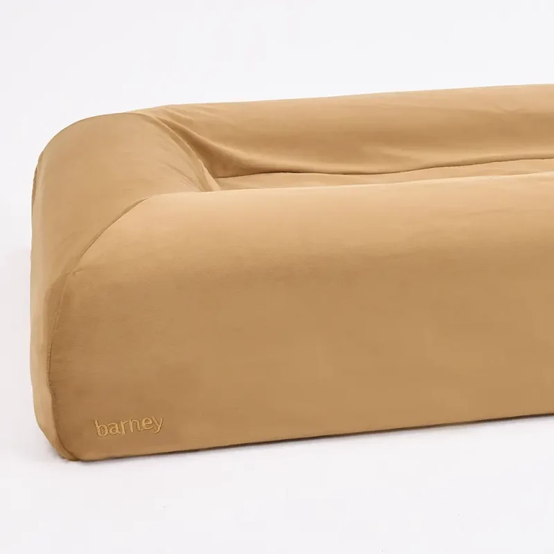 Close-up of the bolster corner of a Butter Slip Cover in Peanut with a barney logo