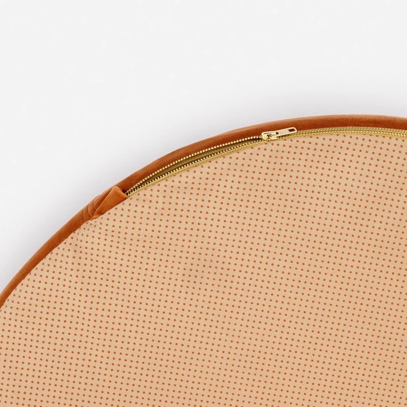 Velvet Cover Curl in Sunset: close-up of the underside edge, a brass zip around the peach base with non-slip dots.