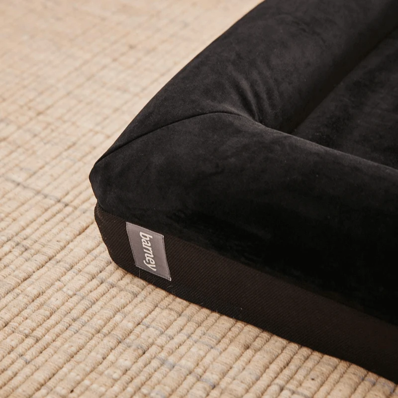Original Cover in Jet Black: close-up of a corner, black velvet bolster over a black woven base with a grey "barney" tab.