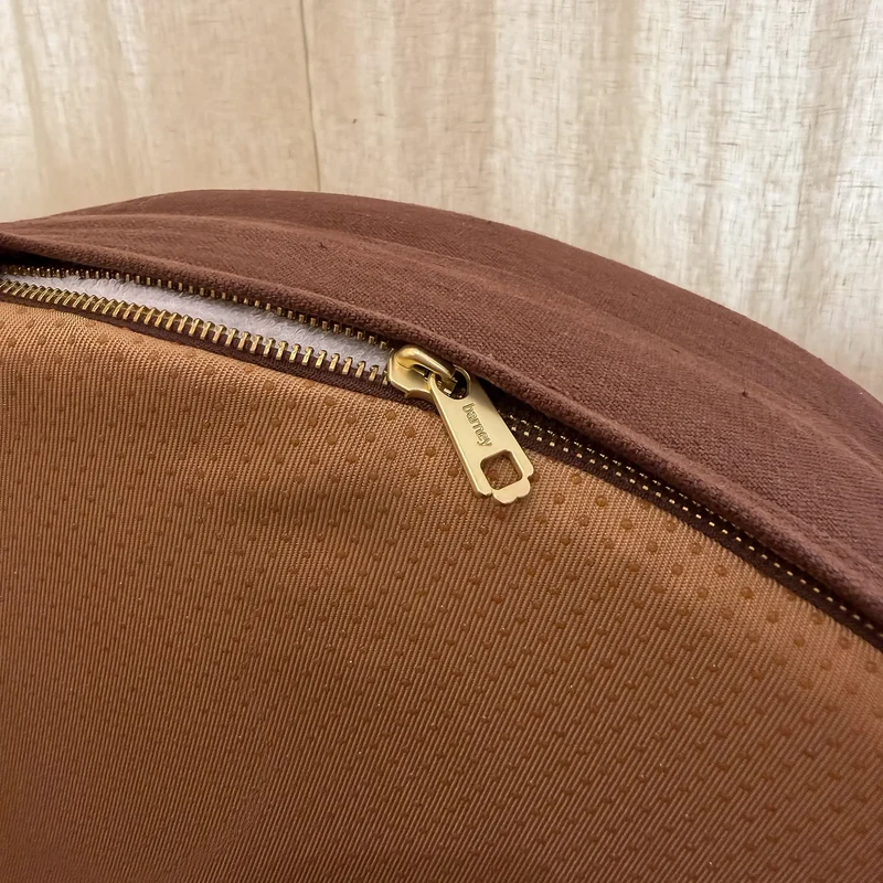 Close-up of a zip cover’s gold zip, part open along the edge of its base