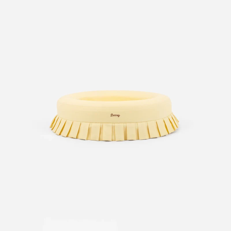 Nostalgia Cover Curl in Buttercream: the round bed on its own, pale yellow with a pleated skirt and a script "Barney" logo.