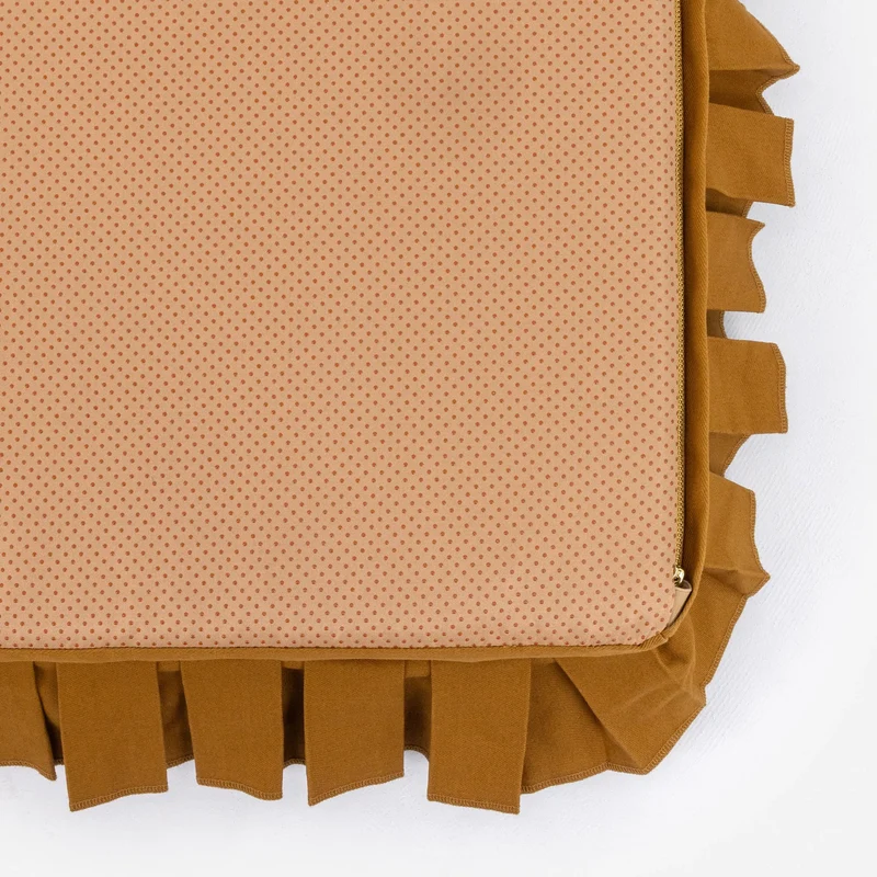 Nostalgia Cover in Toffee: the bed turned over, showing a peach non-slip dotted base framed by the toffee pleated skirt.