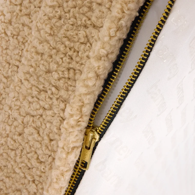Teddy Cover in Rice Pudding: close-up of the brass zip open between the beige teddy fleece and a white "barney" print.