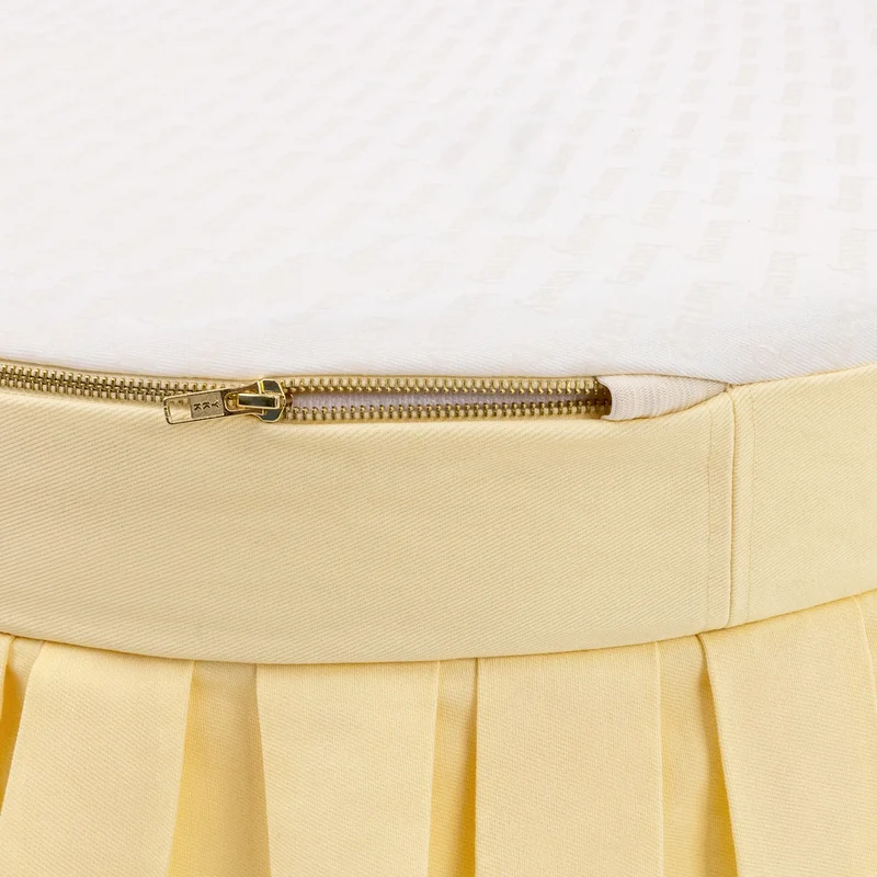 Nostalgia Cover Curl in Buttercream: close-up of the gold zip where the pale yellow side meets the white "barney"-print base.