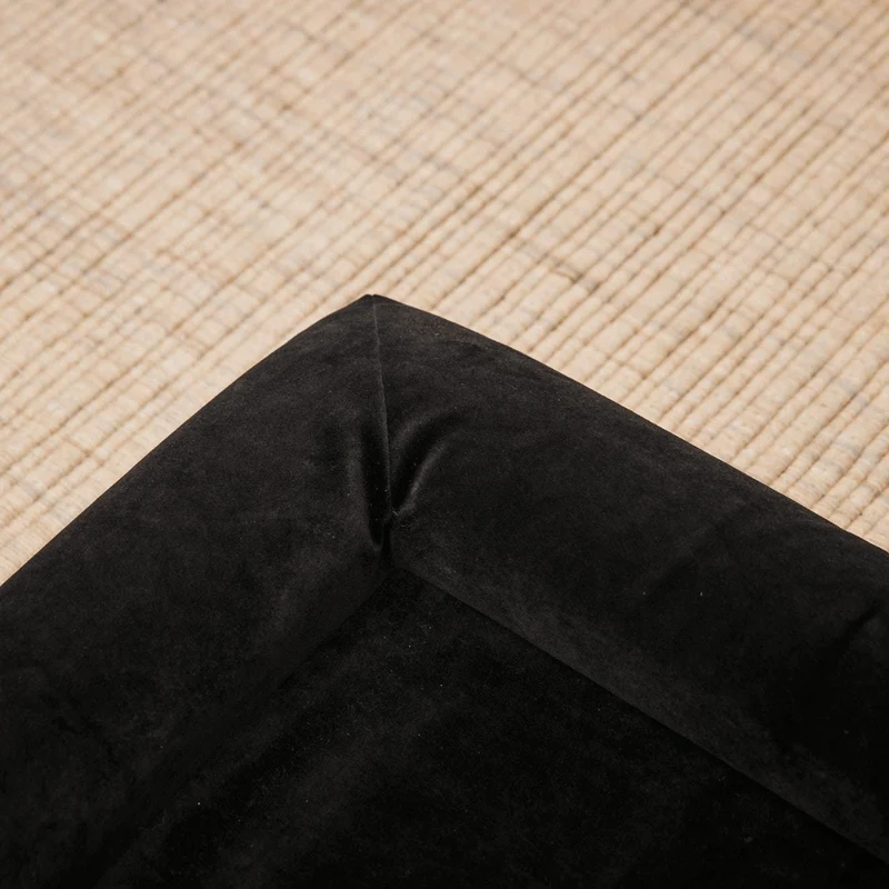 Original Cover in Jet Black: close-up of an empty corner, showing the soft black velvet bolsters, on a woven rug.