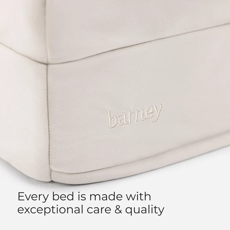 Embroidered barney logo on a Barney Bed in Bone, with the words Every bed is made with exceptional care & quality
